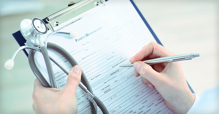 Arzt schreibt Diagnosedaten auf ein Stammblatt